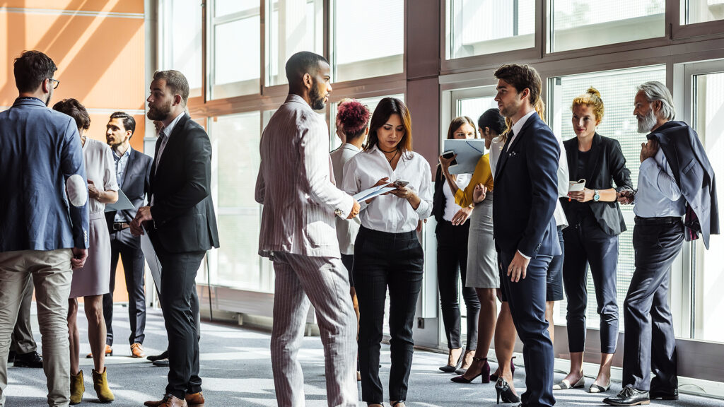 Business professionals networking and discussing documents in a sunlit modern office space.