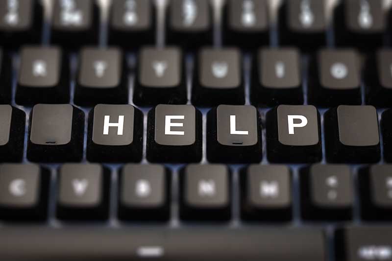 Close-up of a black keyboard with the word “HELP” spelled out in white letters on the keys.