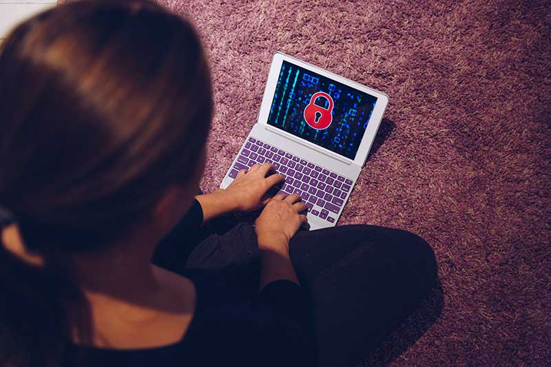 A person using a laptop with a lock icon on the screen, indicating cybersecurity or data protection.