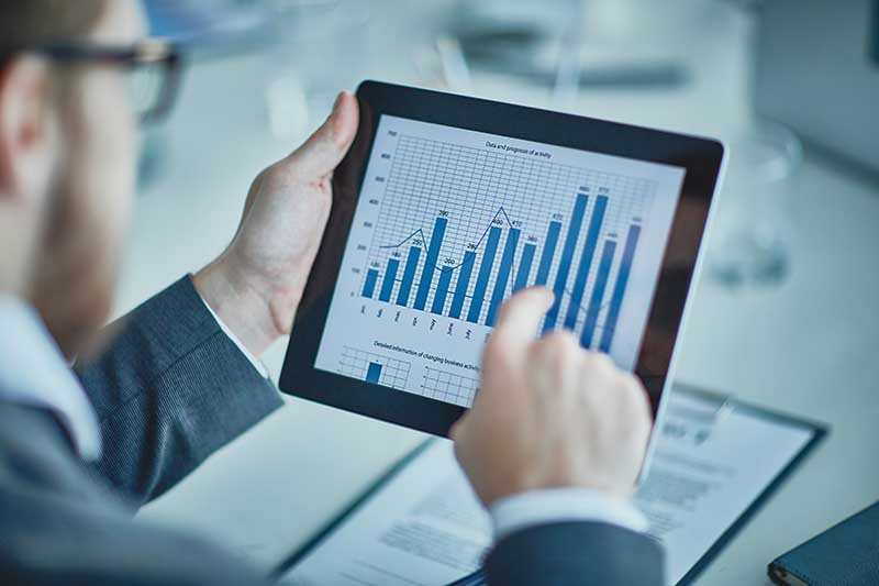 Man holding a tablet displaying a bar chart with business data