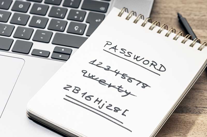 Notepad with passwords written in pen resting on a laptop keyboard.